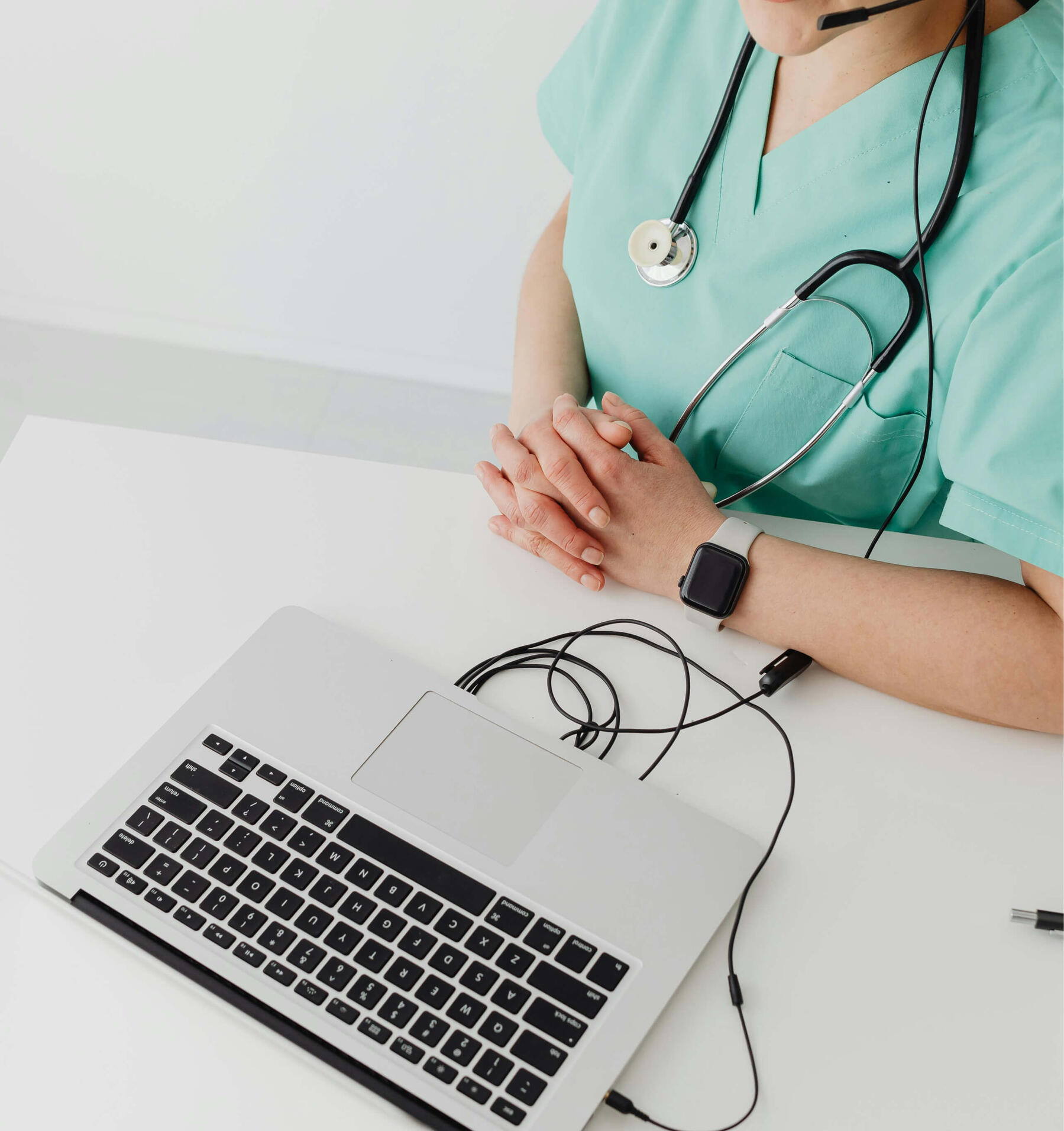 Online Medical Coordination Consultation Healthcare professional wearing scrubs and a stethoscope during an online medical consultation with a laptop.